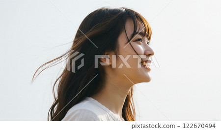 Profile of a hopeful, smiling young woman with her hair blowing in the wind 122670494