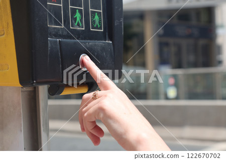 A finger presses the button to let pedestrians cross at a crossing 122670702