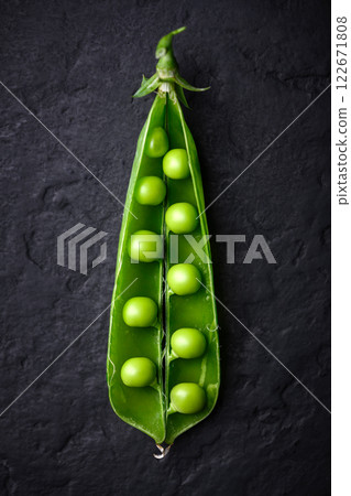 An open pod of green peas on black background close up An open pod of green peas on black background close up 122671808