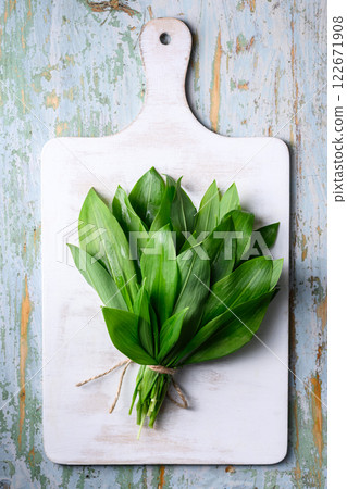 Bunch of fresh bear's wild garlic on white wooden cutting board 122671908