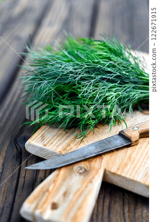 Bunch of green dill with old knife on wooden cutting board close up Bunch of green dill with old knife on wooden cutting board close up 122671915