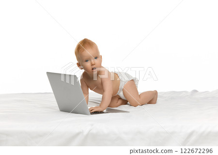Adorable baby, girl in diaper sitting in bed with laptop against white studio background. Early development, education, cartoons Adorable baby, girl in diaper sitting in bed with laptop against white studio background. Early development, education, cartoons 122672296