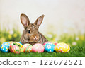 Cute Bunny Surrounded by Colorful Easter Eggs on a Vibrant Grassy Background During Springtime Celebration 122672521