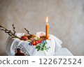 Colorful Easter Eggs and Candlelight in a Decorated Basket With Floral Embroidery 122672524
