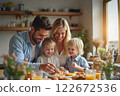 Family Celebrates Easter Together With Joy, Laughter, and Decorated Eggs in Cozy Kitchen 122672536
