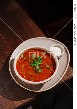 Delicious bowl of spicy tomato soup garnished with fresh herbs served on a wooden table Delicious bowl of spicy tomato soup garnished with fresh herbs served on a wooden table 122672691