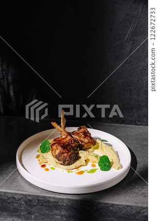 Deliciously plated rack of lamb on a white dish garnished with vibrant sauces in a modern setting Deliciously plated rack of lamb on a white dish garnished with vibrant sauces in a modern setting 122672733