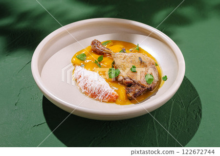 Unique culinary presentation featuring duck breast served with vibrant mango puree and garnished with herbs Unique culinary presentation featuring duck breast served with vibrant mango puree and garnished with herbs 122672744