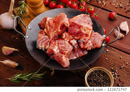 Freshly cut marinated meat in a skillet surrounded by spices and herbs ready for grilling or cooking Freshly cut marinated meat in a skillet surrounded by spices and herbs ready for grilling or cooking 122672747