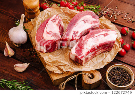 Fresh cuts of meat arranged on a wooden board with herbs and spices for a barbecue preparation 122672749