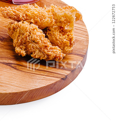 Crispy fried chicken served on a wooden platter with fresh tomato slices and a refreshing dip 122672753