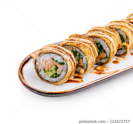 Delicious sushi rolls topped with creamy sauce and served on a white plate 122672757
