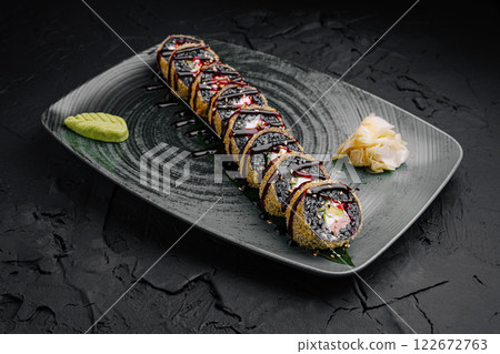 Delicious sushi roll plated beautifully on a dark textured surface with wasabi and pickled ginger 122672763