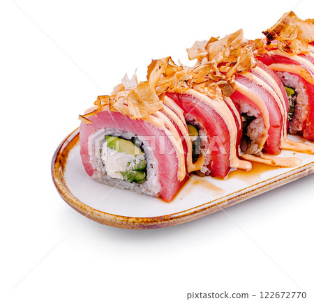 Sushi roll with fresh tuna, avocado, and garnished with bonito flakes on a white plate 122672770