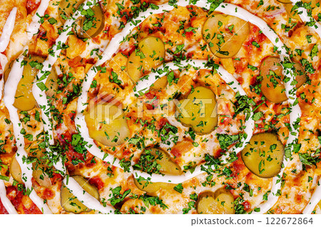 Unique pizza topped with pickles, herbs, and creamy sauce presented in a spiral pattern on a rustic wooden table Unique pizza topped with pickles, herbs, and creamy sauce presented in a spiral pattern on a rustic wooden table 122672864