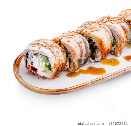 Delicious sushi rolls presented on a white plate drizzled with sauce and sprinkled with sesame seeds 122672881