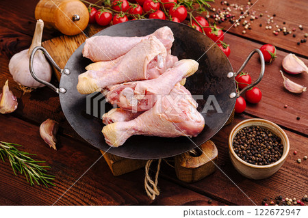 Fresh chicken drumsticks and ingredients arranged on a rustic wooden table in preparation for cooking Fresh chicken drumsticks and ingredients arranged on a rustic wooden table in preparation for cooking 122672947