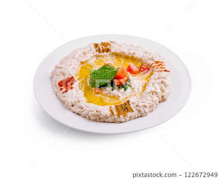 Rich and creamy tahini dip served with olive oil, herbs, and spices on a white plate Rich and creamy tahini dip served with olive oil, herbs, and spices on a white plate 122672949