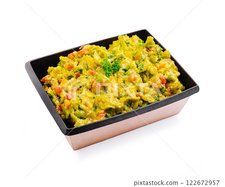 Fresh guacamole with diced vegetables served in a black container highlighting vibrant colors and textures 122672957