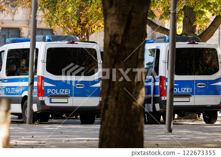 Scene back view many german police van cars serve at city street center downtown on sunny day. Civil emergency law security traffic service vehicle Europe. Event safety service Scene back view many german police van cars serve at city street center downtown on sunny day. Civil emergency law security traffic service vehicle Europe. Event safety service 122673355