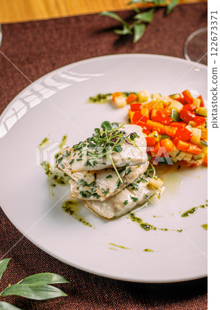 Portion of white fish with sauted vegetables 122673371