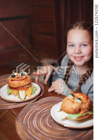 A girl child is sitting in a cafe and is going to A girl child is sitting in a cafe and is going to 122674298