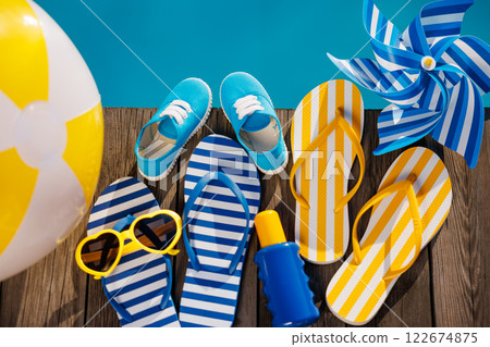 Beach flip-flops and sunglasses on wooden planks near swimming pool Beach flip-flops and sunglasses on wooden planks near swimming pool 122674875