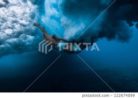 Woman dives without surfboard under powerful ocean wave. Duck dive under crashing wave Woman dives without surfboard under powerful ocean wave. Duck dive under crashing wave 122674899
