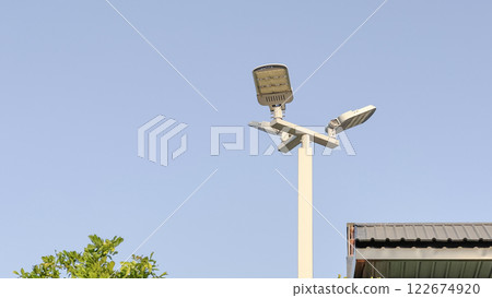 A bright streetlight, securely mounted on a metal pole, provides safety and visibility for a local community. This image highlights urban infrastructure, energy efficiency. 122674920