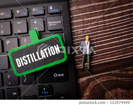 Miniature people and black keyboard with the word DISTILLATION on a wooden background. 122674999