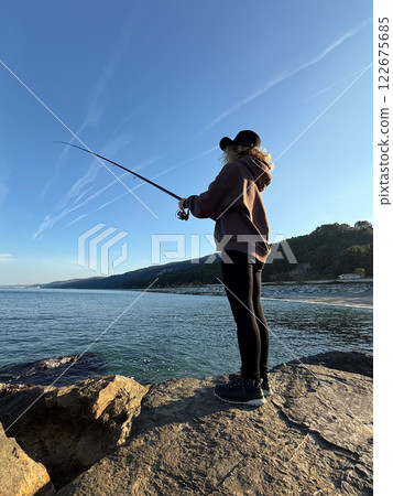 Young happy woman is fishing at sea during spring vacation Young happy woman is fishing at sea during spring vacation 122675685