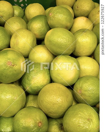 Lime on the counter at the market. Sale of citrus fruits. Healthy food, vitamins and juice. Background, a pattern of a group of fruits, limes. Green fruit. Limes, lemons and oranges 122675927