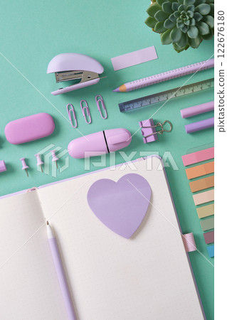 Blank notepad page for your text with purple school and office stationery on mint green background. Violet heart shaped sticker. Space for your text. 122676180