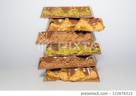 Stack of Trend Dubai chocolate with pistachio, peanut butter, caramel, chocolate spread and kataifi dough. Different flavours. Traditional confectionery. Stack of Trend Dubai chocolate with pistachio, peanut butter, caramel, chocolate spread and kataifi dough. Different flavours. Traditional confectionery. 122676525