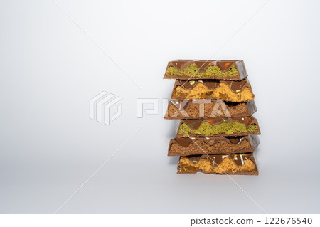Stack of Trend Dubai chocolate with pistachio, peanut butter, caramel, chocolate spread and kataifi dough. With copy space. confectionery. Stack of Trend Dubai chocolate with pistachio, peanut butter, caramel, chocolate spread and kataifi dough. With copy space. confectionery. 122676540