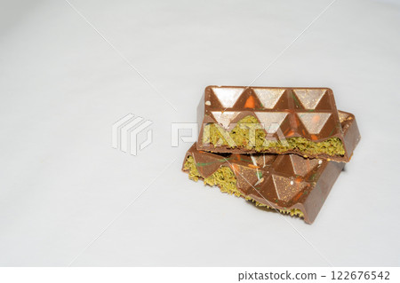 Trend Dubai chocolate bar with pistachio paste, tahini and kataifi dough on white background. Confectionery and sweets. 122676542