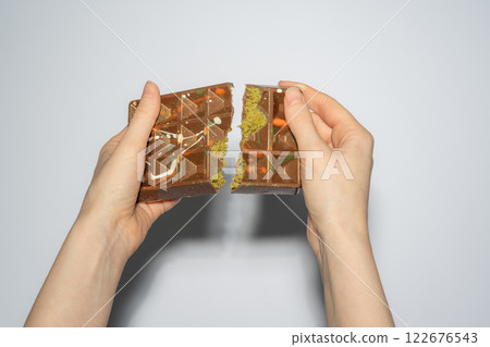 Famous Dubai chocolate with pistachio, tahini and kadaif broken in woman hands. Confectionery handmade sweets, chocolatier 122676543