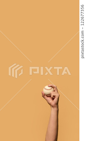 Hand holding baseball high, fingers gripping seams with precision, symbolizing control and readiness for action against warm-toned background. Hand holding baseball high, fingers gripping seams with precision, symbolizing control and readiness for action against warm-toned background. 122677356