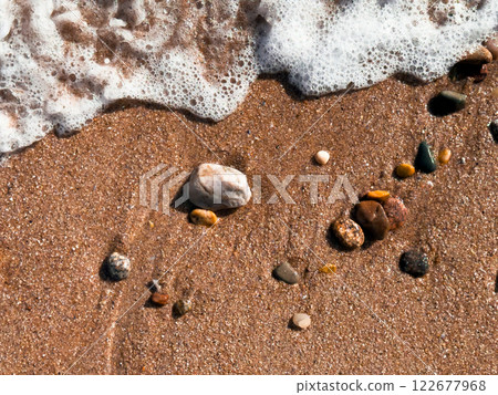 Ocean waves gently lapping on sandy beach with colorful pebbles Ocean waves gently lapping on sandy beach with colorful pebbles 122677968