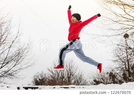 Woman wearing sportswear exercising outside during winter Woman wearing sportswear exercising outside during winter 122678070