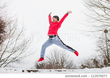 Woman wearing sportswear exercising outside during winter Woman wearing sportswear exercising outside during winter 122678071