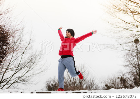 Woman wearing sportswear exercising outside during winter Woman wearing sportswear exercising outside during winter 122678072