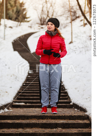 Woman wearing sportswear exercising outside during winter 122678073