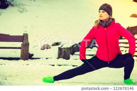 Woman wearing sportswear exercising outside during winter 122678146