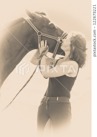 Jockey young girl kissing and hugging brown horse 122678221