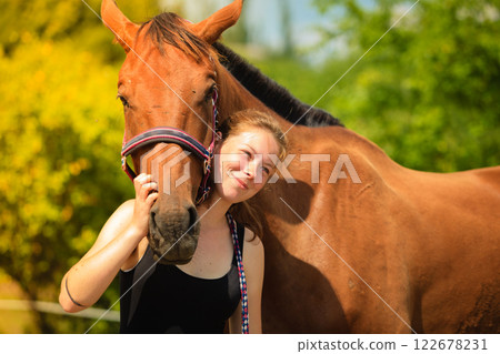 Jockey young girl petting and hugging brown horse Jockey young girl petting and hugging brown horse 122678231