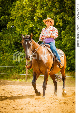 Cowgirl doing horse riding on countryside meadow 122678387