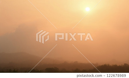 Golden sunrise illuminating foggy landscape with rolling hills 122678989