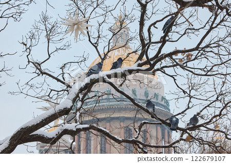 a snow-covered New Year's city decorated for the celebration of the new year, pigeons on a tree, the golden dome of St. Isaac's Cathedral a snow-covered New Year's city decorated for the celebration of the new year, pigeons on a tree, the golden dome of St. Isaac's Cathedral 122679107