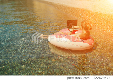 Woman laptop sea. Freelancer woman in sunglases floating on an inflatable big pink donut with a laptop in the sea. People summer vacation rest lifestyle concept Woman laptop sea. Freelancer woman in sunglases floating on an inflatable big pink donut with a laptop in the sea. People summer vacation rest lifestyle concept 122679372